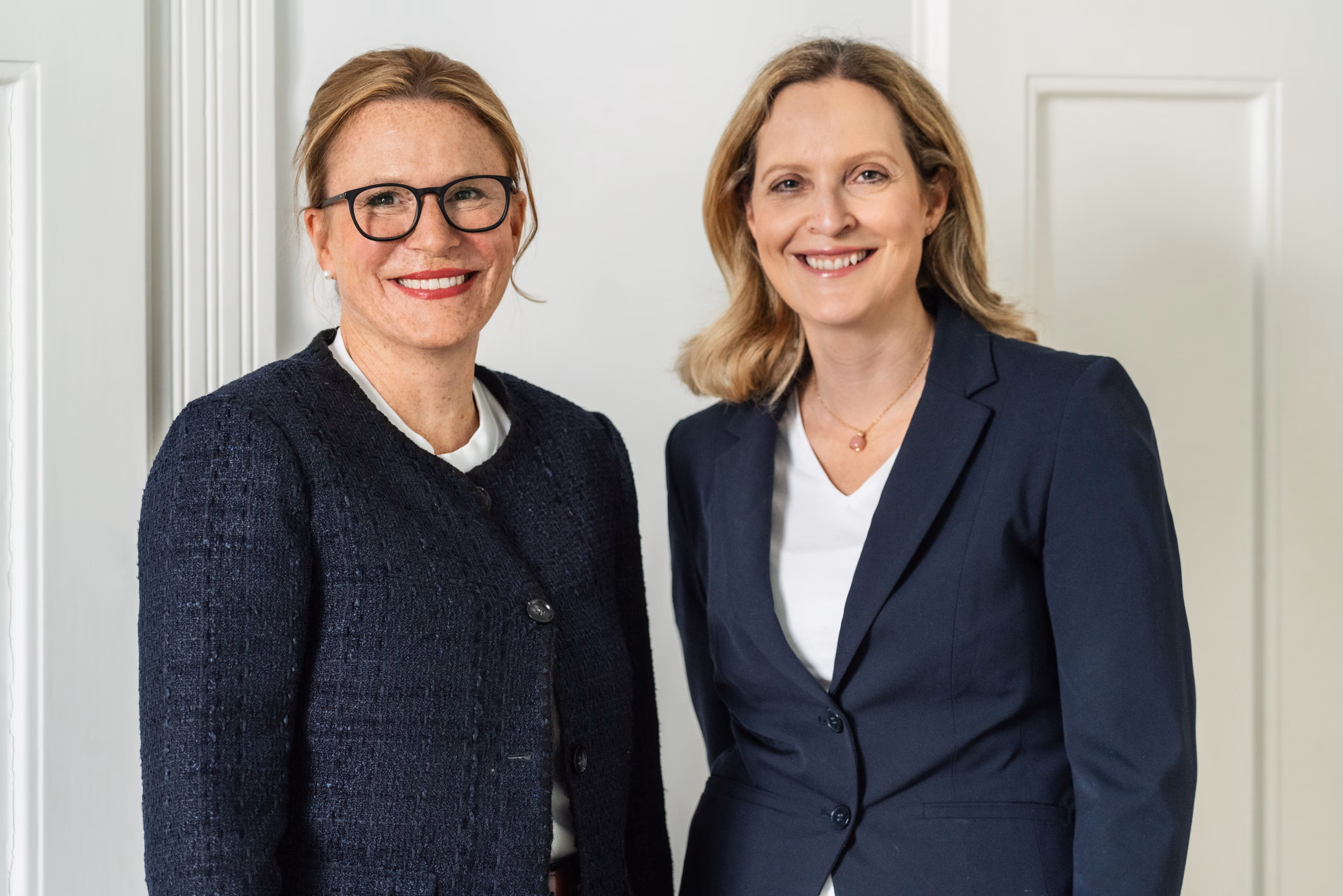 Rechtsanwältinnen Nina Schlottke-Wegner und Magdalena Reinarz stehen nebeneinander in der Kanzlei